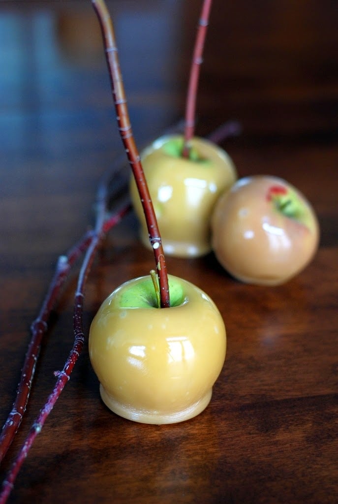 three caramel apples on a wood table