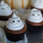 chocolate cupcakes with boiled icing piped into ghosts with candy eyes