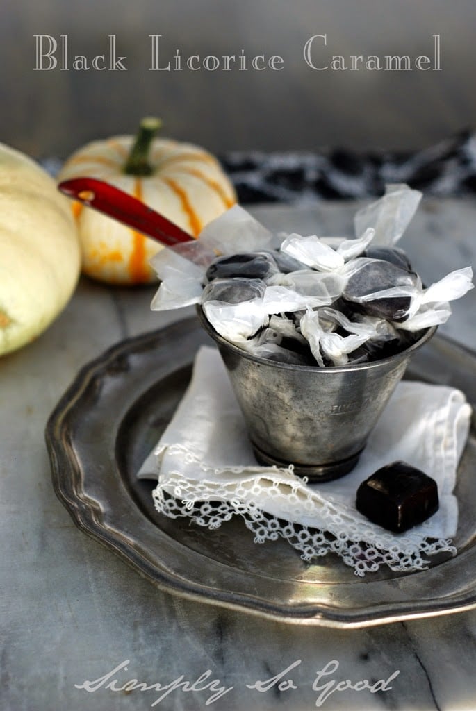 licorice caramels in a tin cup on a white clothes with pumpkins in back ground.