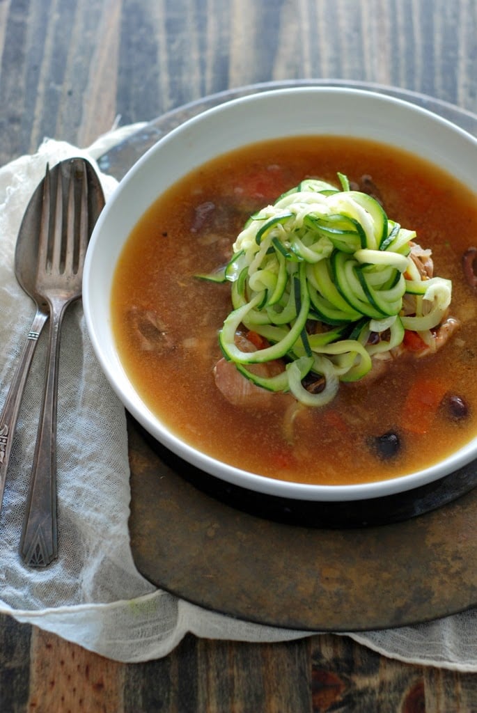 braised chicken in bowl with juices and zucchini noodles