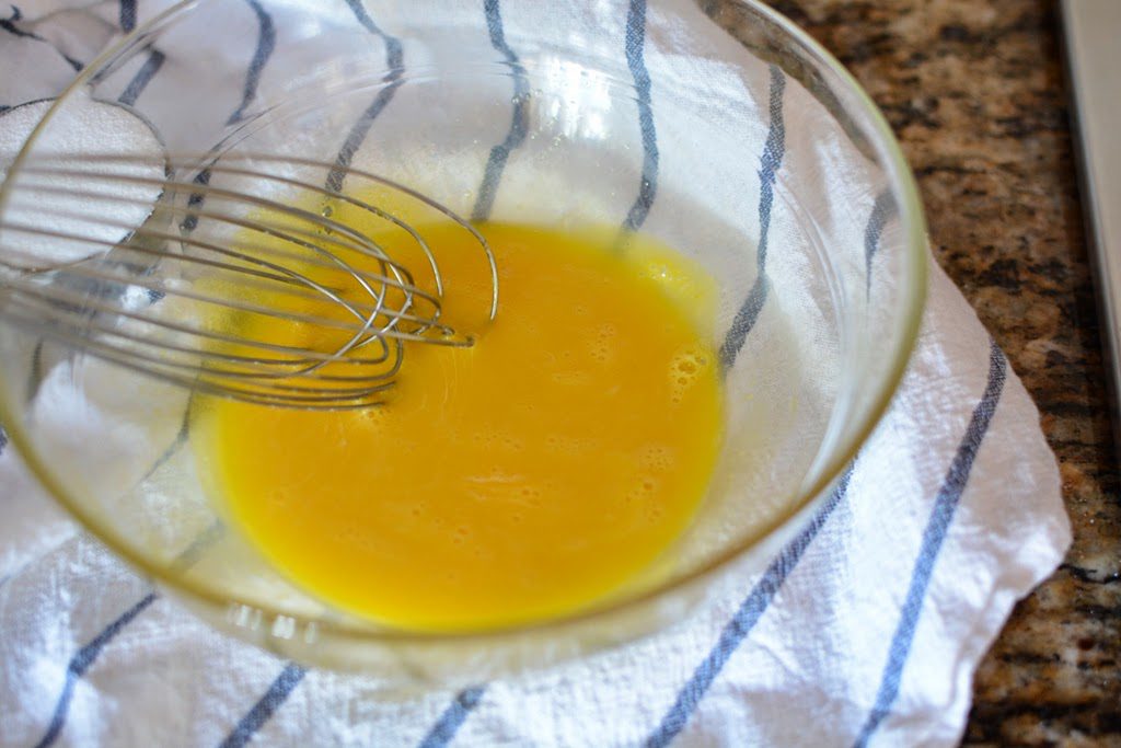 Eggs whisked in a glass bowl.