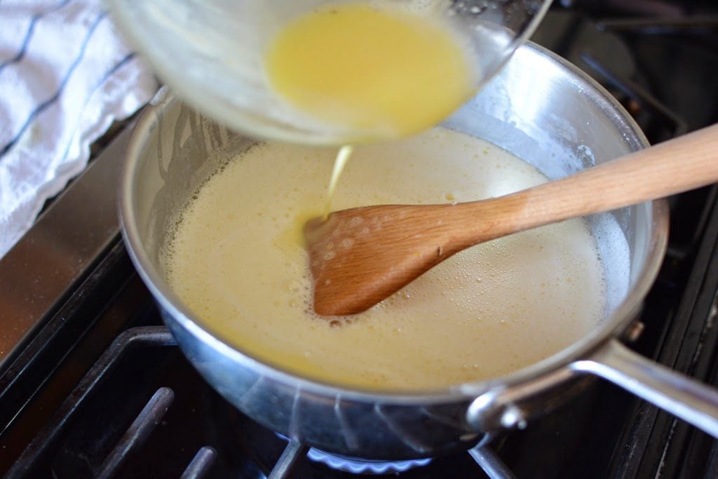 Adding egg mixture to a low skillet on the stovetop.