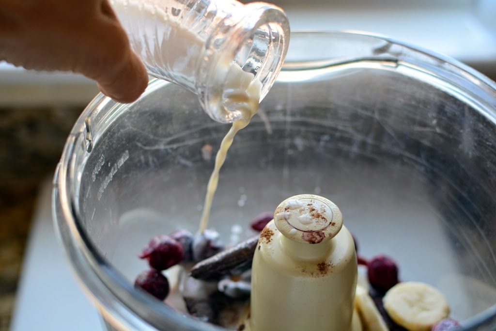 almond milk pouring into bowl of food processor