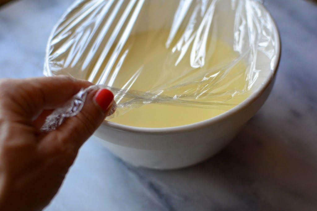 Cooked ice cream custard in white bowl with plastic wrap