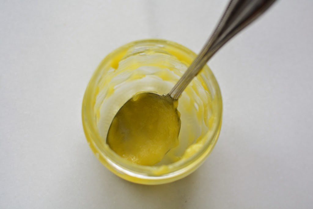 Empty jar of lemon curd with metal spoon.