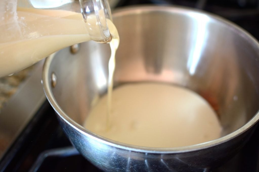 Adding milk to a metal bowl.