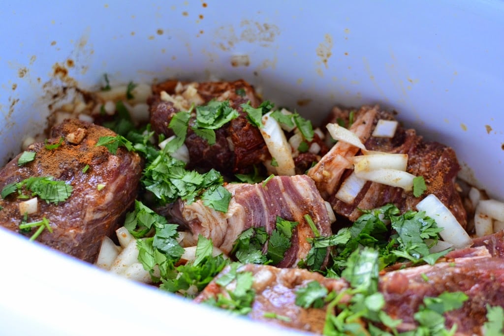 uncooked beef with spices and cilantro in crockpot