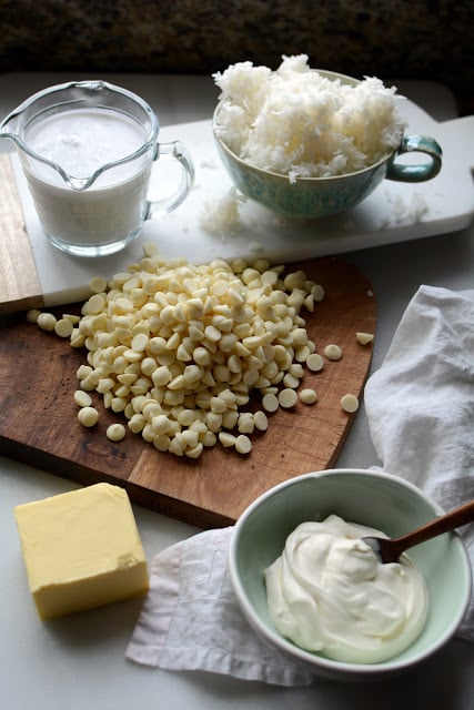 Measured ingredients of coconut milk, coconut flakes, white chocolate chips, butter, and sour cream.