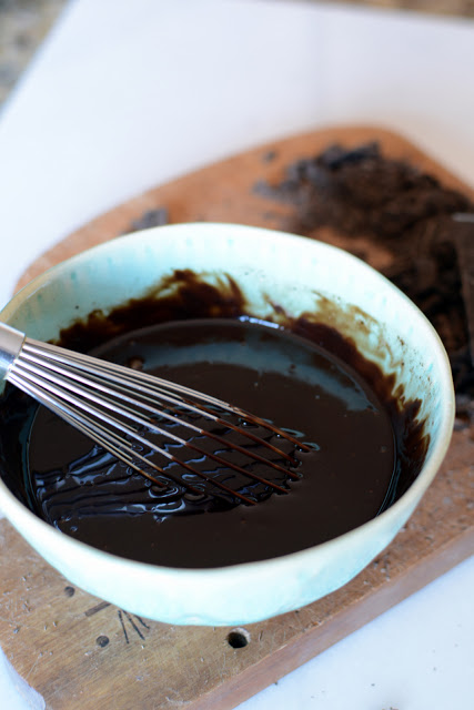 Bowl of chocolate ganache stirred with a whisk.