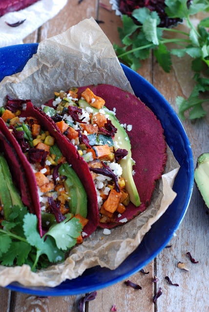 two veggie tacos with hibiscus tortillas on blue plate