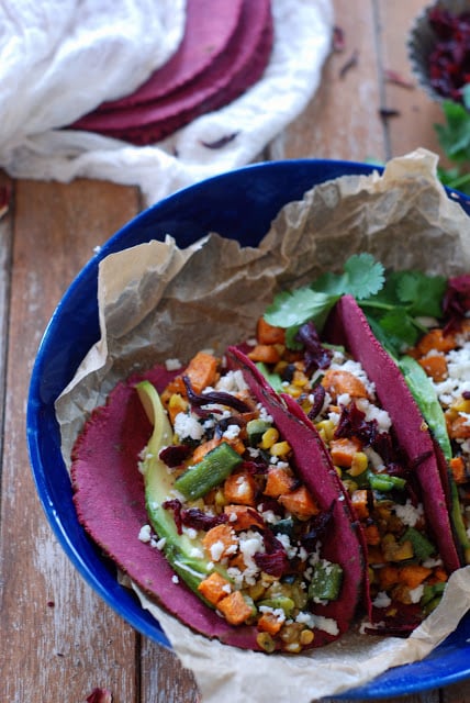 Two veggie tacos with hibiscus tortillas i a blue bowl