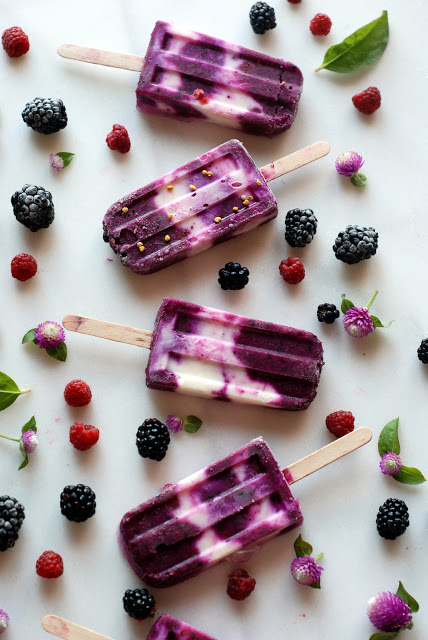 Pitaya and yogurt popsicles with berries scattered around