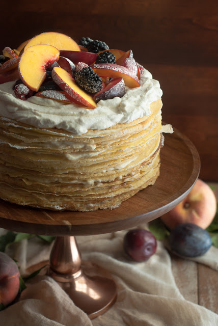 Layered Einkorn crepe cake topped with peaches and plums