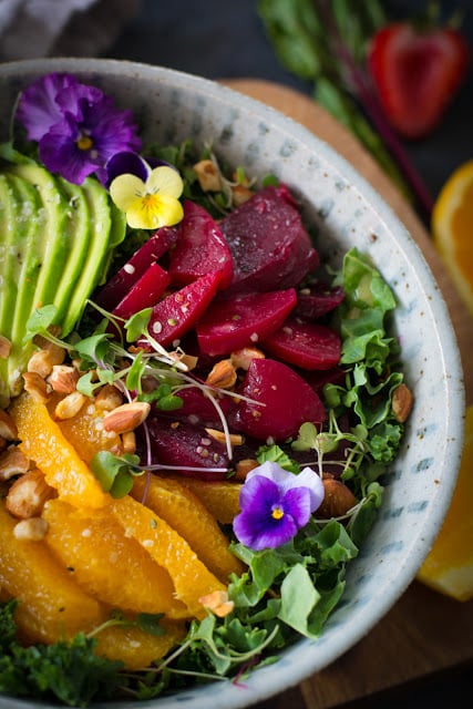 large bowl with kale, beets, avocado, oranges, pansies