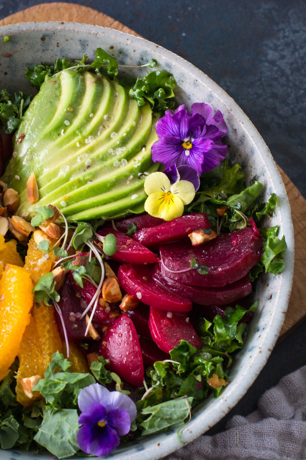 Avocado slices, beets, fruit, pansies on kale