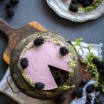 Overhead shot of Chocolate Zucchini Cake with Blackberry Buttercream on a board with blackberries and fresh thyme