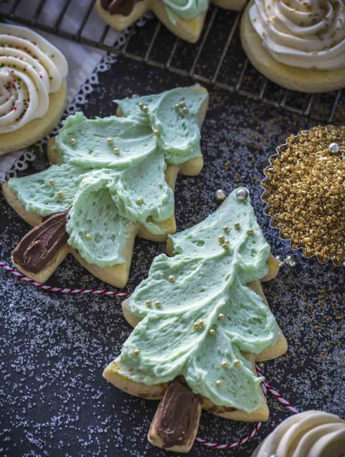 Tree cut out sugar cookies with green icing and golden sprinkles