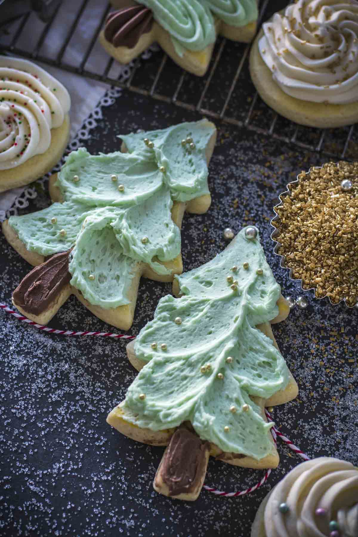 Tree cut out sugar cookies with green icing and golden sprinkles