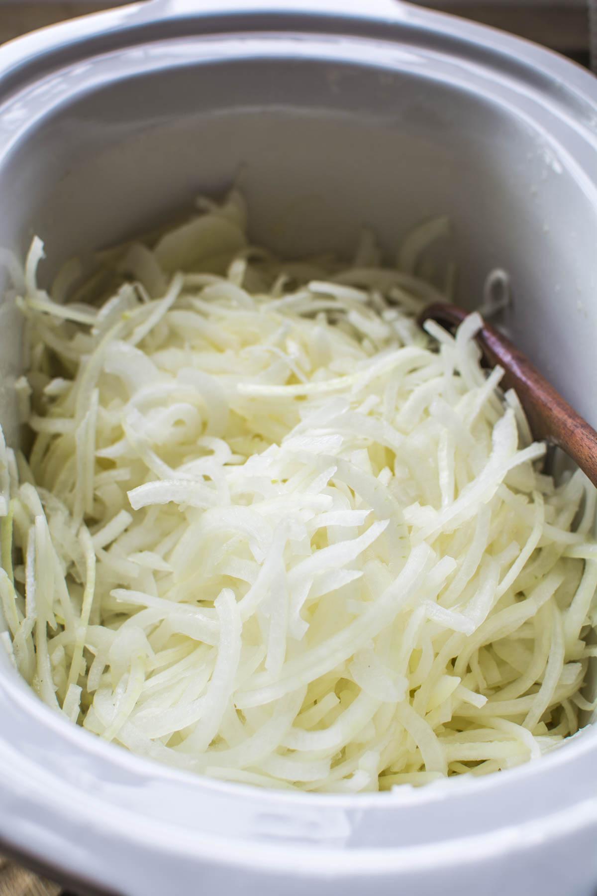 French onion soup in a Crockpot filled with sliced onons