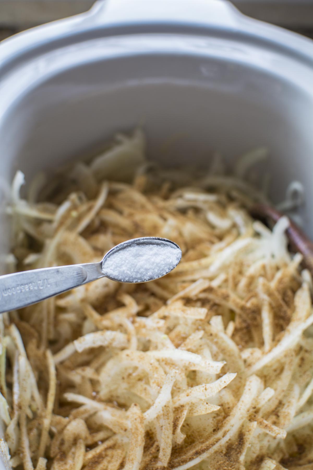 French onion soup in a Crockpot with onion slices sprinkled with coconut sugar and salt