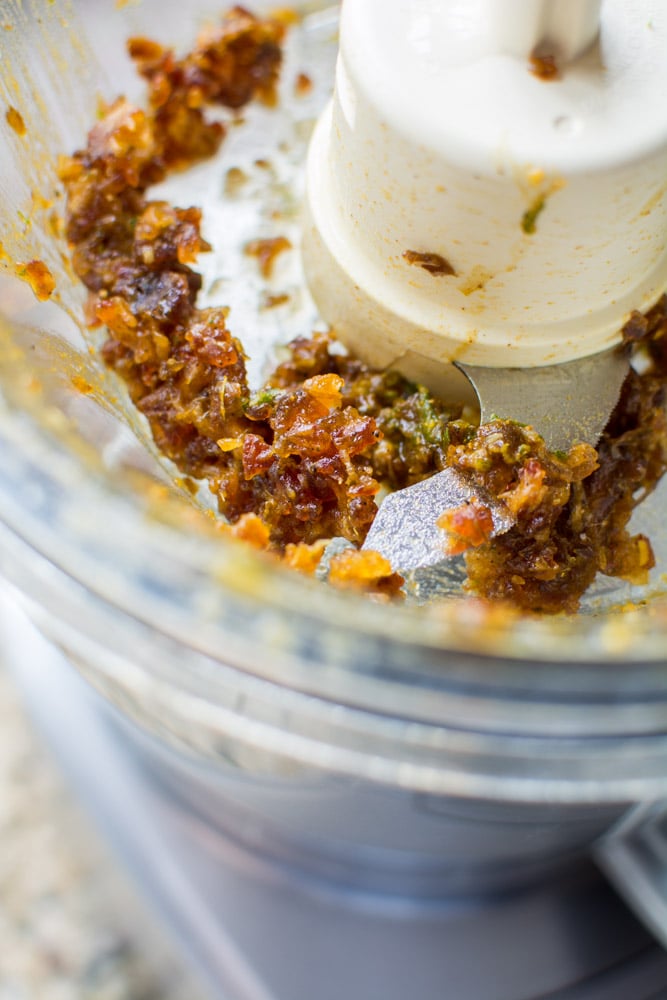 Food processor filled with dates with spoonful of curry