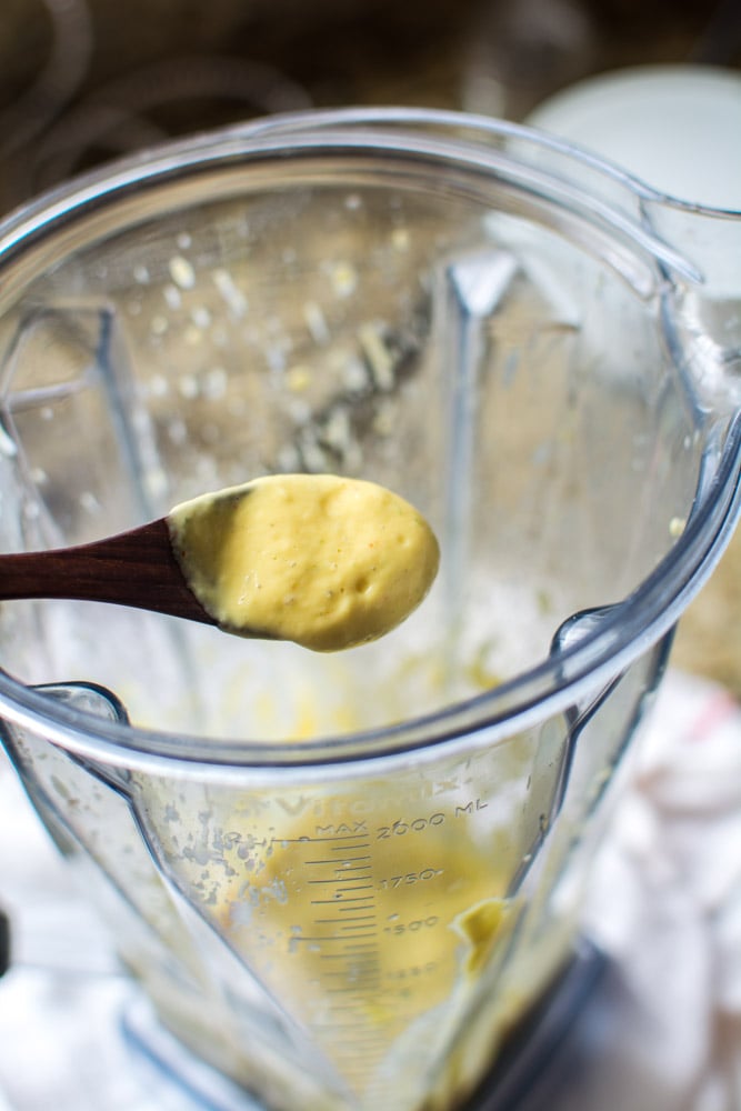 Small wooden spoonful of mango tahini sauce over a blender