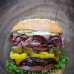 Grilled Pastrami Burger with Spicy Brown mayo, on wood background.