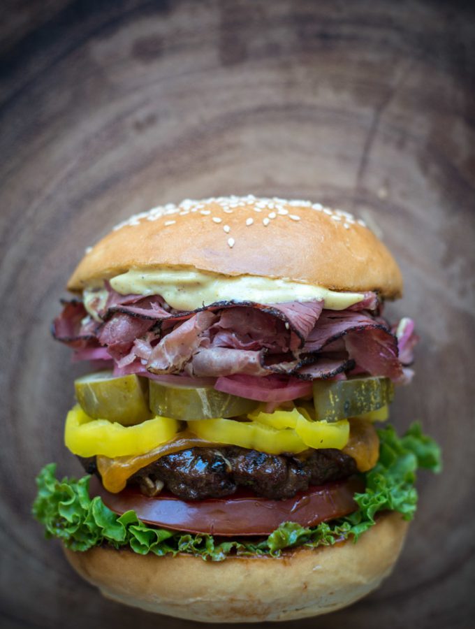 Grilled Pastrami Burger with Spicy Brown mayo, on wood background.