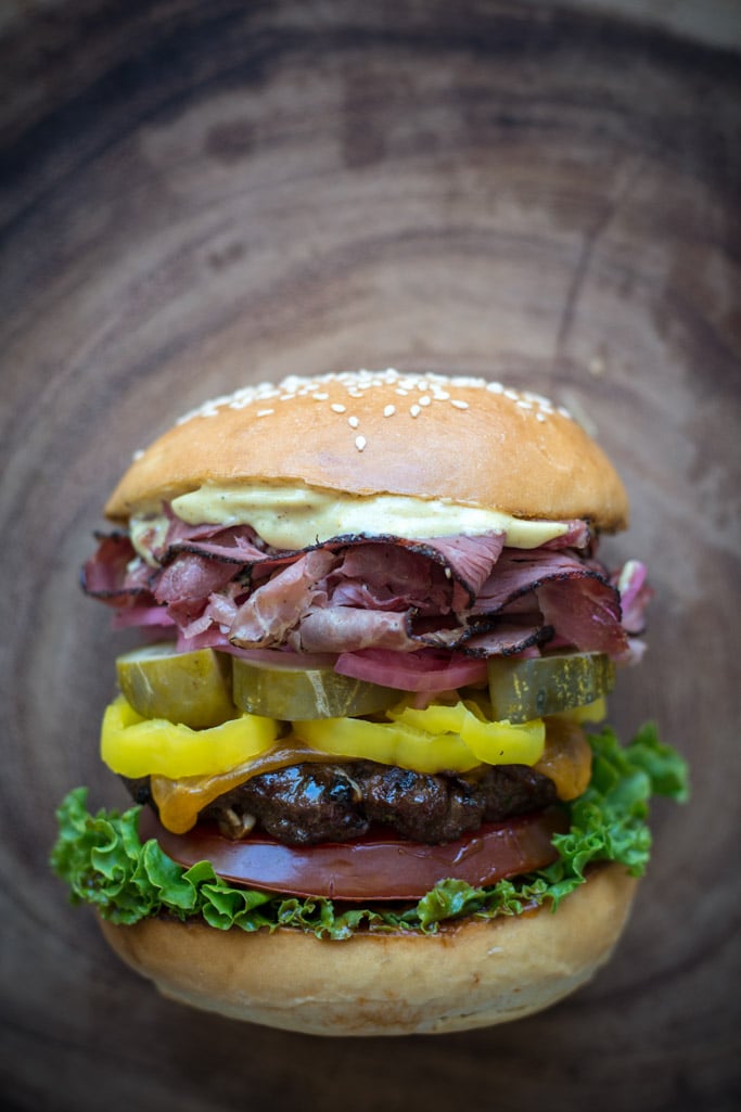 Grilled Pastrami Burger with Spicy Brown mayo, on wood background.