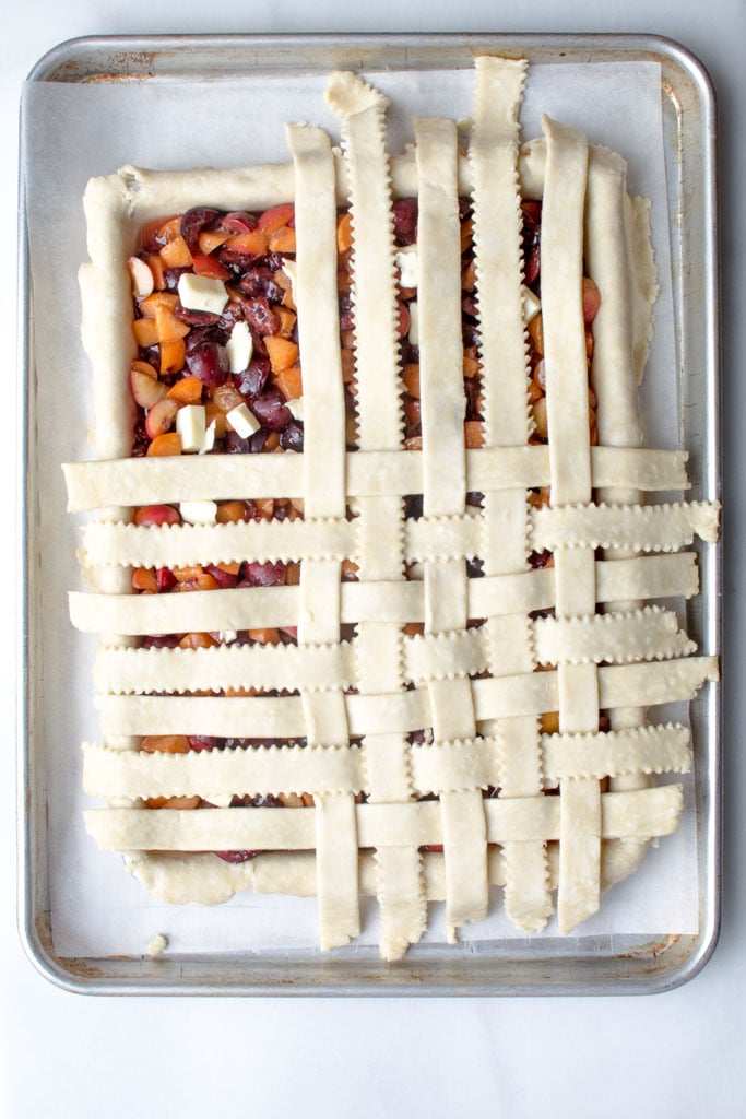 Covering the cherry apricot slab pie with the dough lattice.