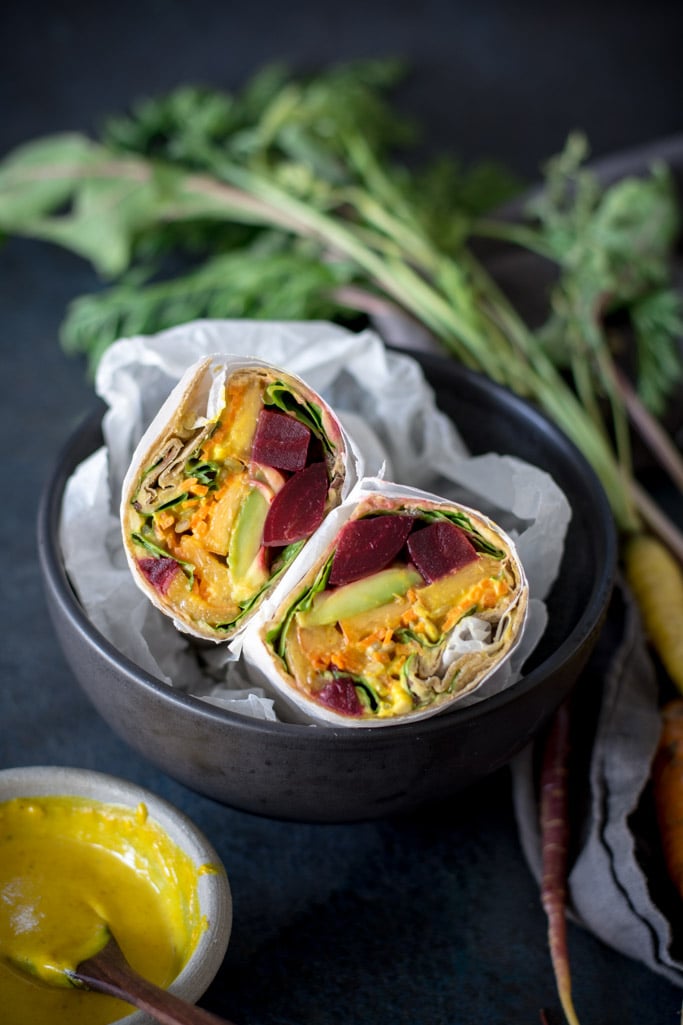 Beet, Peach, and Avocado Wrap with Turmeric Tahini Sauce cut in half in a black bowl