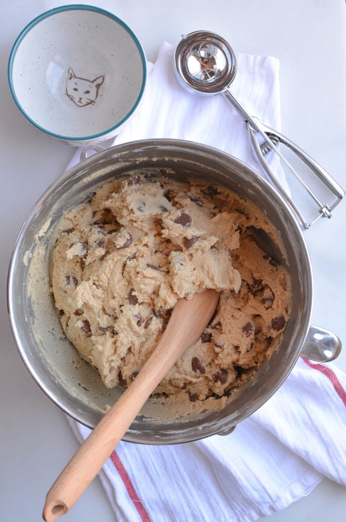 Chocolate chips being stirred into jumbo chocolate chop cookie dough