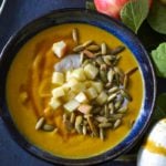 Pumpkin Apple Soup with pumpkin seeds, diced apples, in a bowl