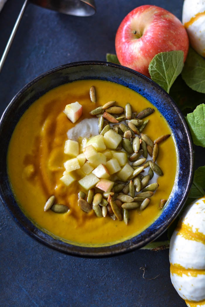 Pumpkin Apple Soup with pumpkin seeds, diced apples, in a bowl