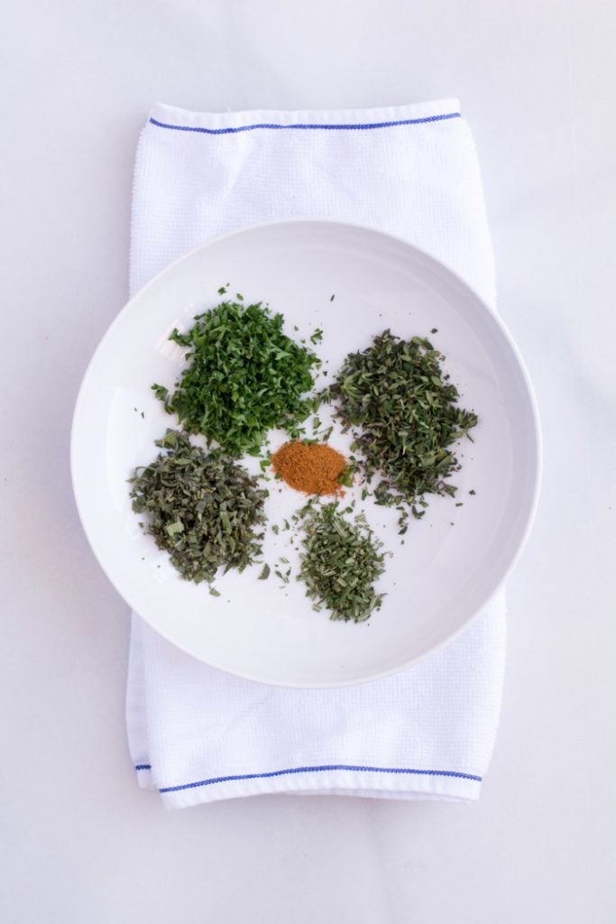Pulled herbs on a white plate.