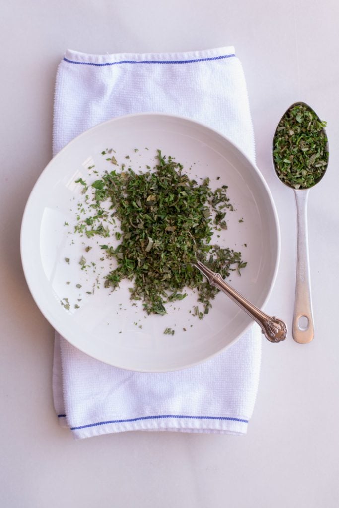 Fresh herbs blended together on a white plate.