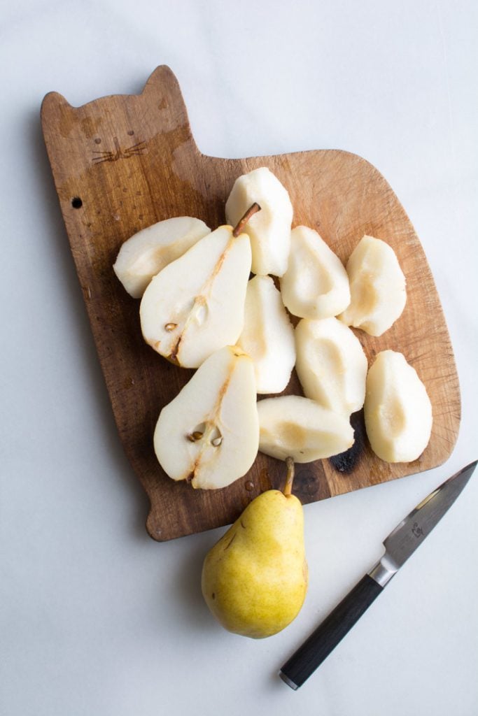 Several pears cut in half on a wood cutting board.