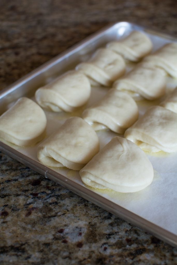 Rolls of dough set on a baking sheet.
