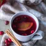 Cranberry wassail in a mug with cinnamon stick and cranberries