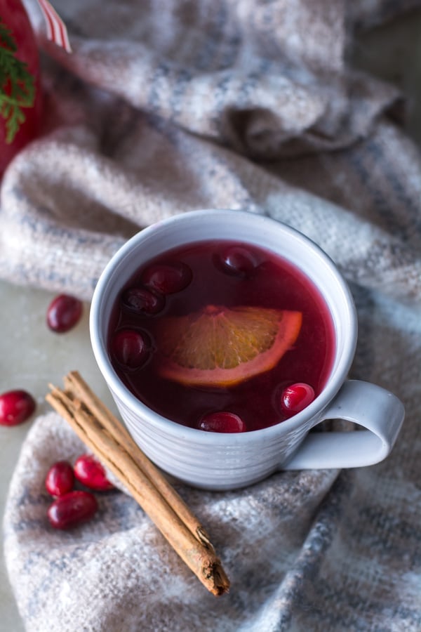 Cranberry wassail in a mug with cinnamon stick and cranberries