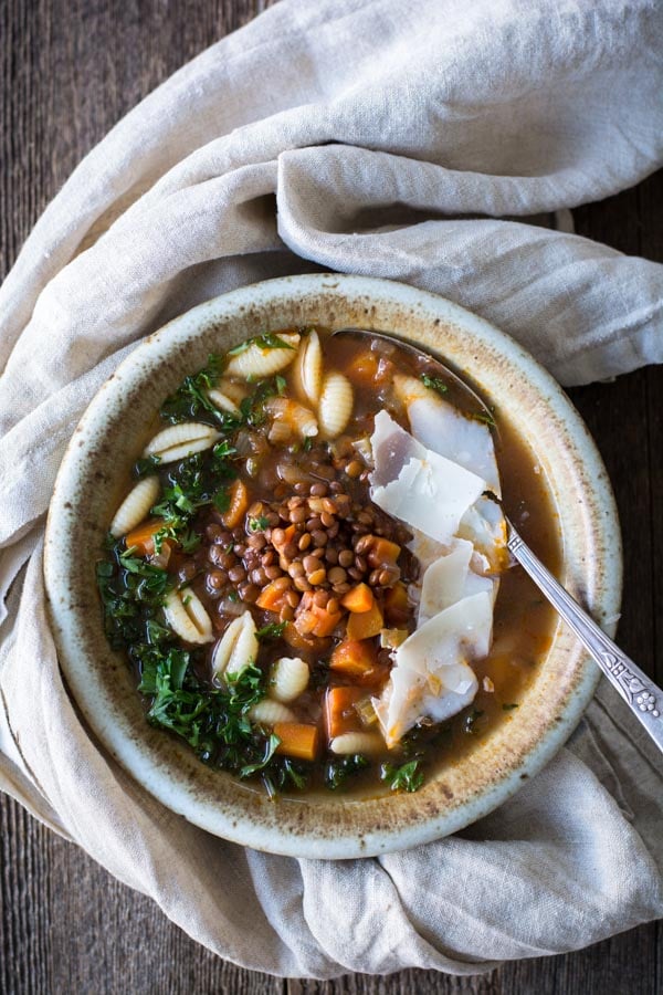 Large bowl of minestrone soup with lentils with a spoon.