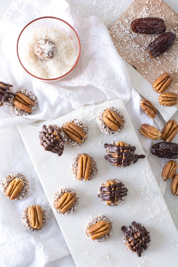 Pecans on date bites on platter with drizzled chocolate
