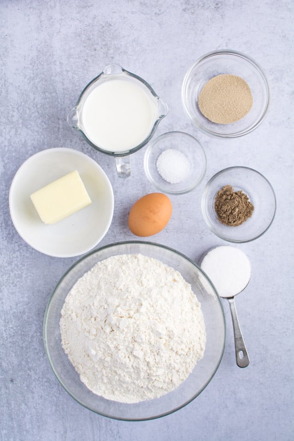Dough ingredients measured in bowls: Flour, butter, ground cardamom, yeast, salt, milk, and one whole egg.