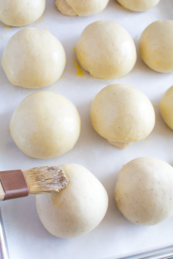 Egg wash applied to risen buns.
