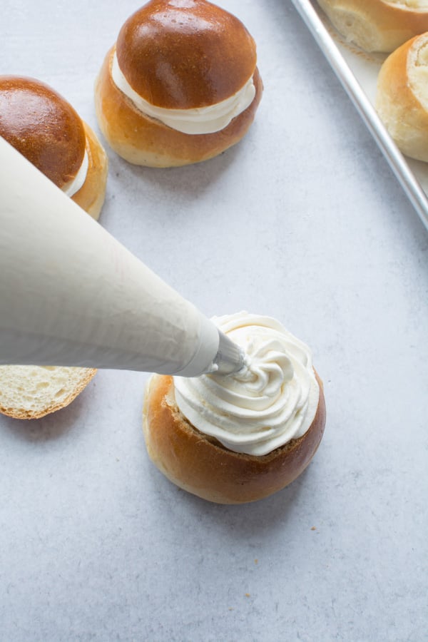 Piping bag adding whipped cream to the bun.