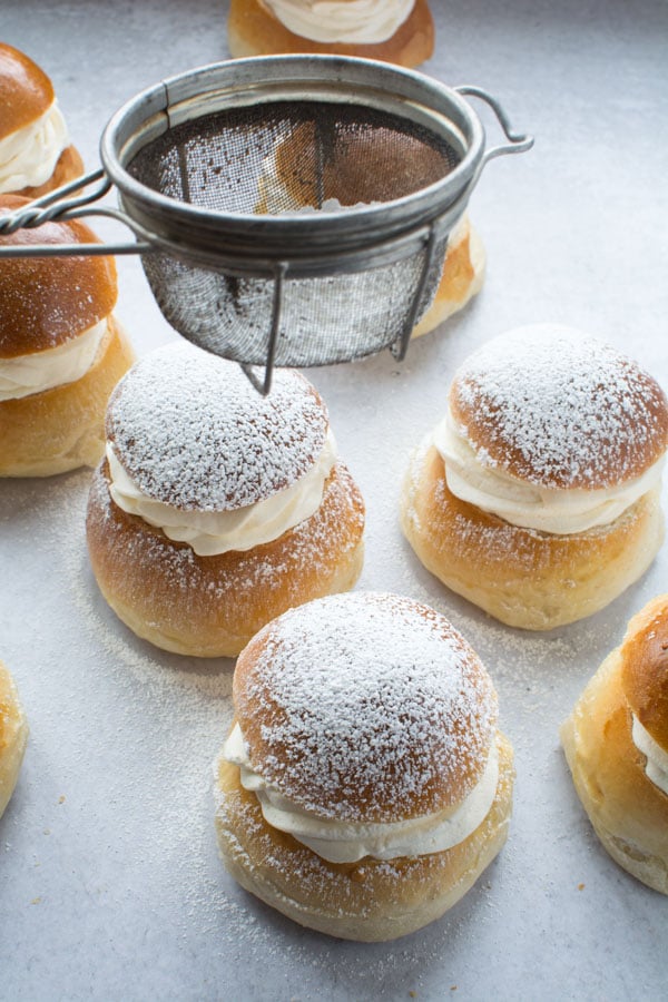 Using a sieve to dust powdered sugar over the sweet buns.