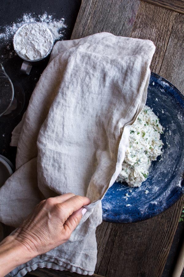 mixed focaccia dough in blue bowl with towel covering