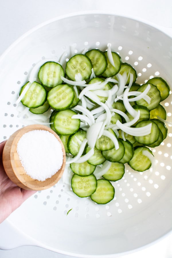 Ripple slices of cucumber white onion with salt in a wooden bowl