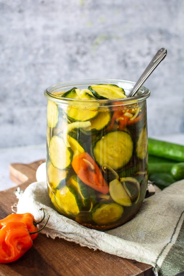 Large jar of spicy sweet bread and butter pickles with habanero peppers and onions.