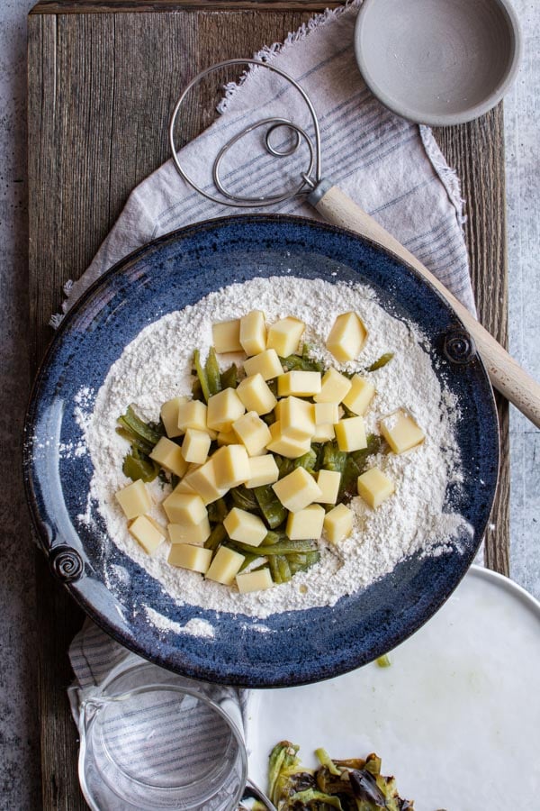 blue bowl with white flour with chunks of cheddar cheese and green chiles on top